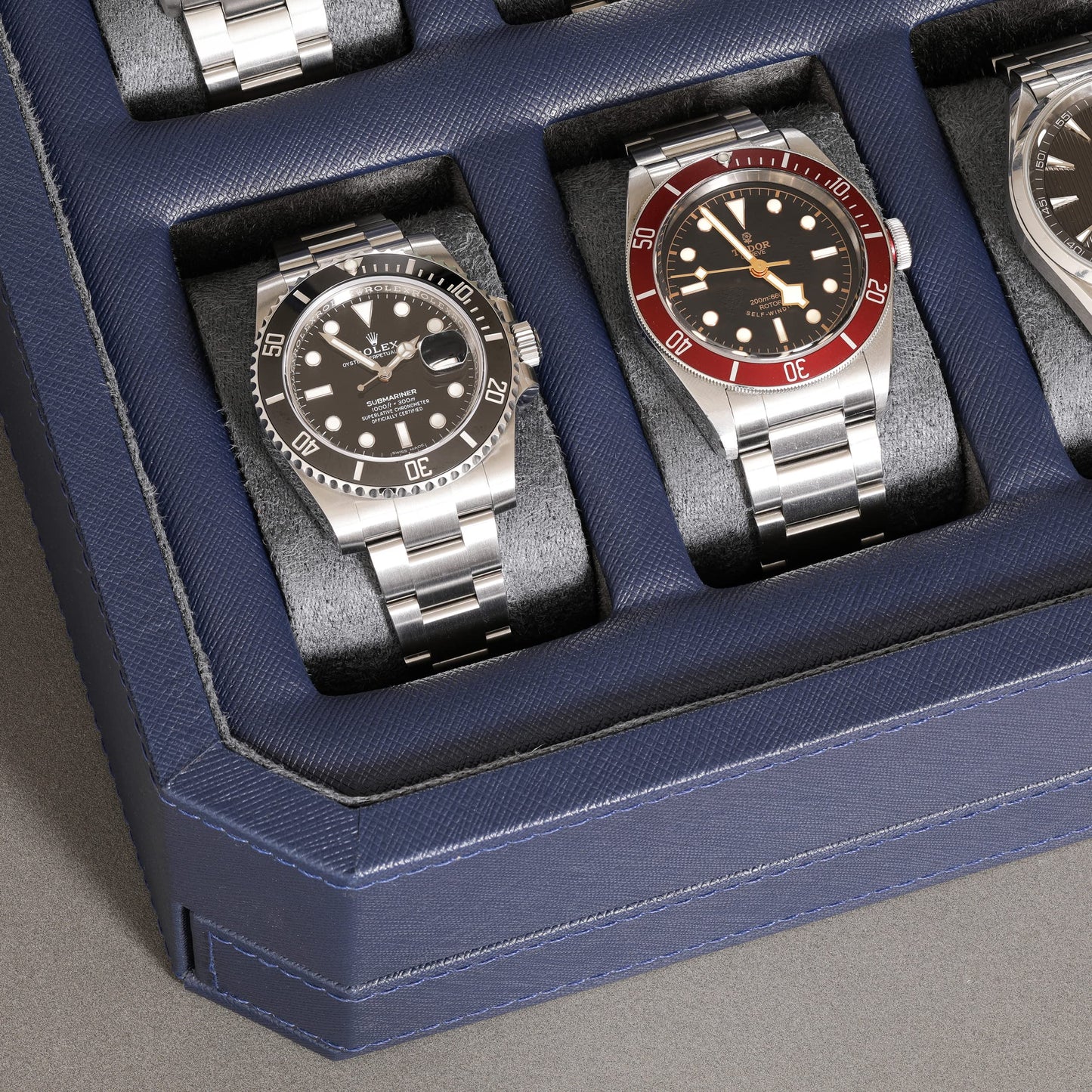 ROTHWELL 12-Slot Leather Watch Box with Valet Drawer is a luxury watch case display organizer. It features a microsuede liner and can hold men's accessories and jewelry in dark blue/grey.