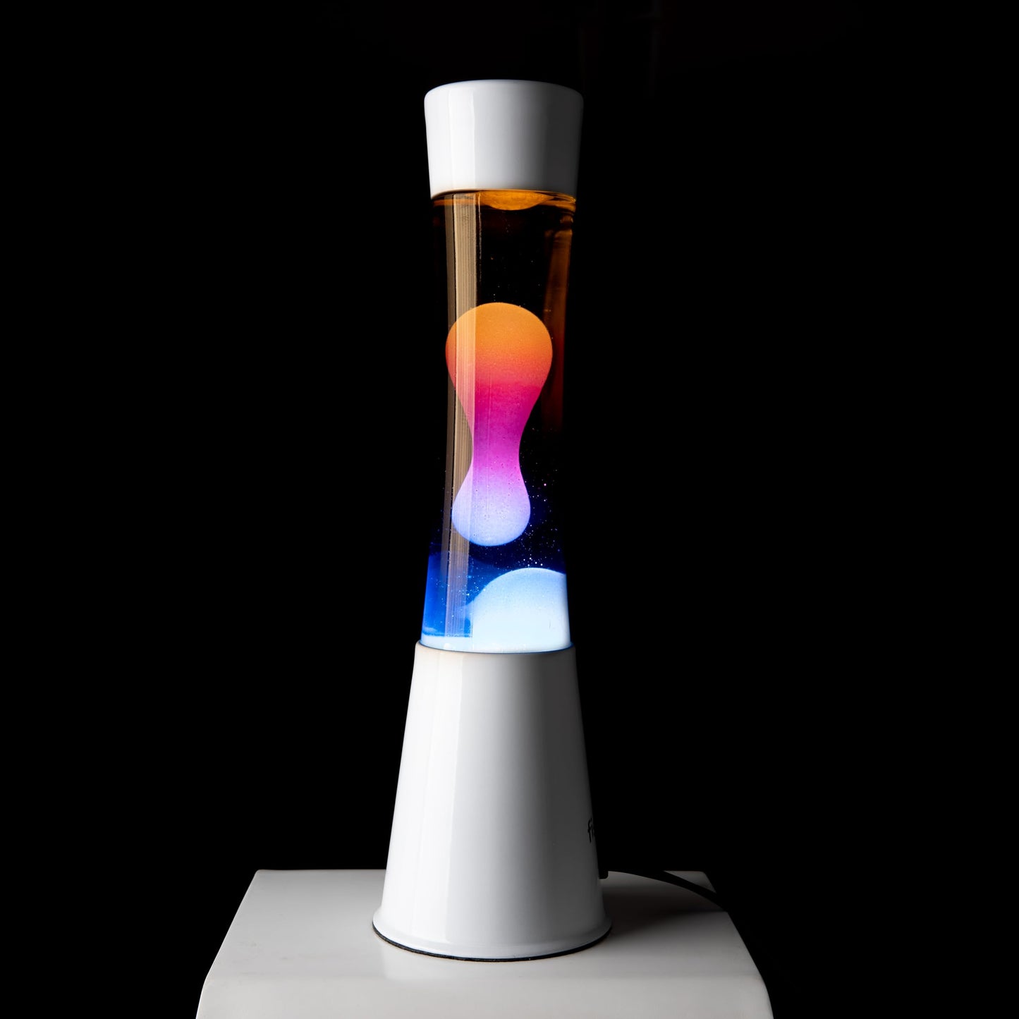 FISURA - Multicolored lava lamp. White base and glass with multicolored gradient effect. Lamp for relaxation. Comes with spare bulb. 11 cm x 11 cm x 39.5 cm.