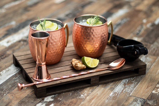 Buddy's Bar - Moscow Mule Complete Set features 2 x 500 ml cocktail cups, 27 cm bar spoon, 5 cl jigger & black lime squeezer, food-safe and comes in a gift box. Copper hammered design.