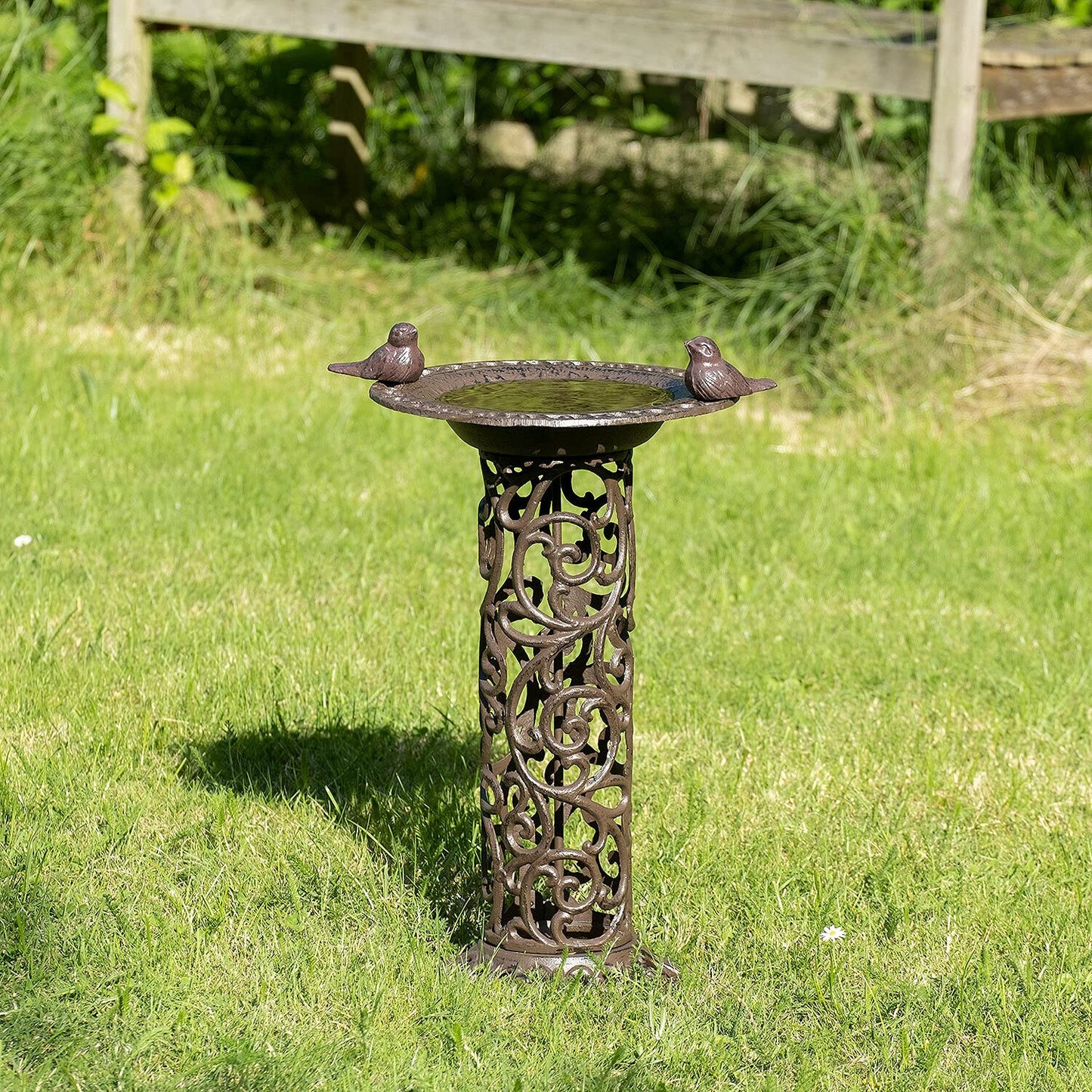 Large bird bath with decorative birds made of cast iron. Metal water bowl for feeding and garden decoration.