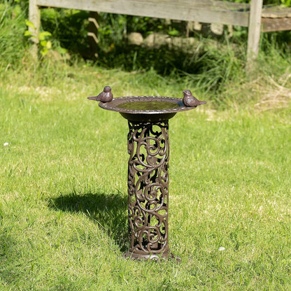Large bird bath with decorative birds made of cast iron. Metal water bowl for feeding and garden decoration.